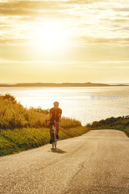 太阳下山，女性骑自行车骑上陡峭的山坡