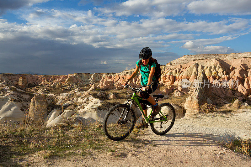 女自行车手在一个岩石景观旅行