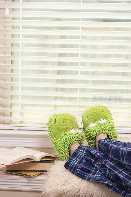 女人放松，在她的睡衣和有趣的拖鞋读书。