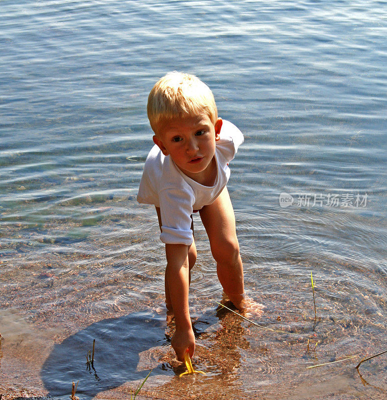 金发男孩在水里玩。夏天的观点。