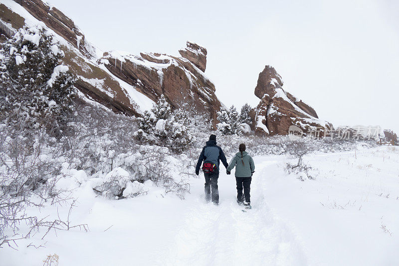 冬天，一对穿着雪鞋的夫妇在科罗拉多州莫里森的红岩公园徒步旅行