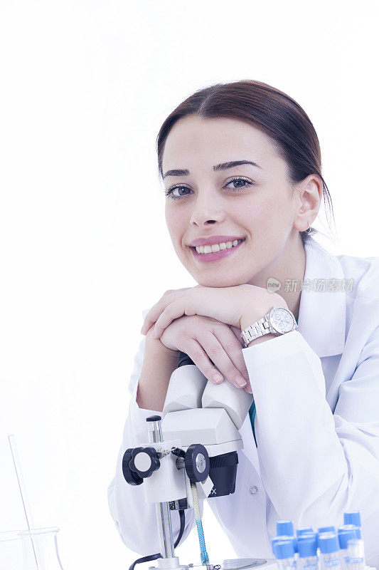 年轻的女研究员微笑与显微镜在白色的背景
