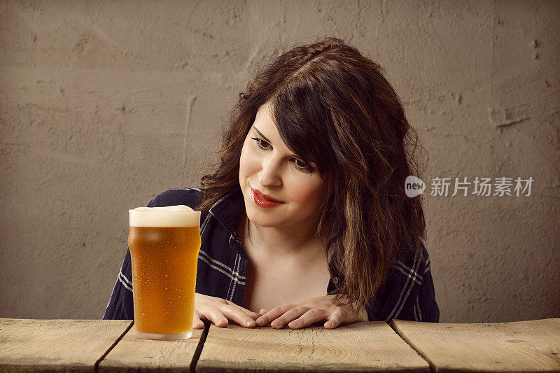 一个年轻女人坐在酒吧里喝啤酒