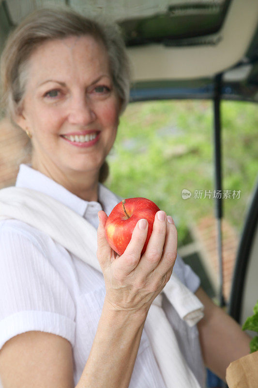 老年妇女举着新鲜的苹果