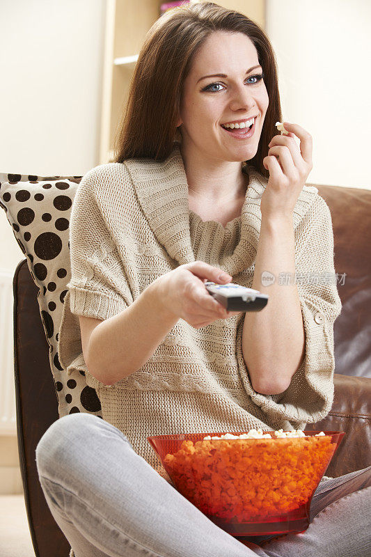 年轻女子一边吃爆米花一边看电视