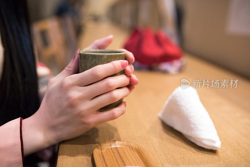 年轻女子在餐厅里喝着茶暖手