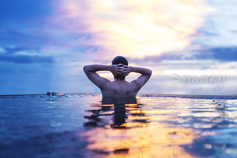 一个男人在夏天日落天空下的水里放松