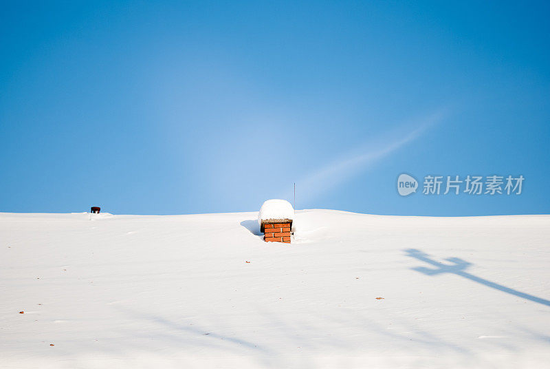 有烟囱的部分屋顶在阳光明媚的冬日里覆盖着积雪
