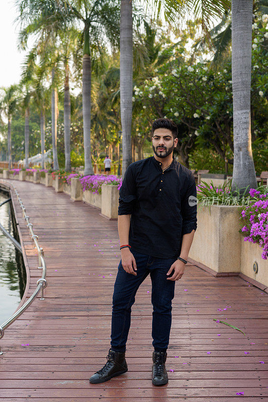 年轻英俊的印度男子站在泰国曼谷安静公园的木板路上思考