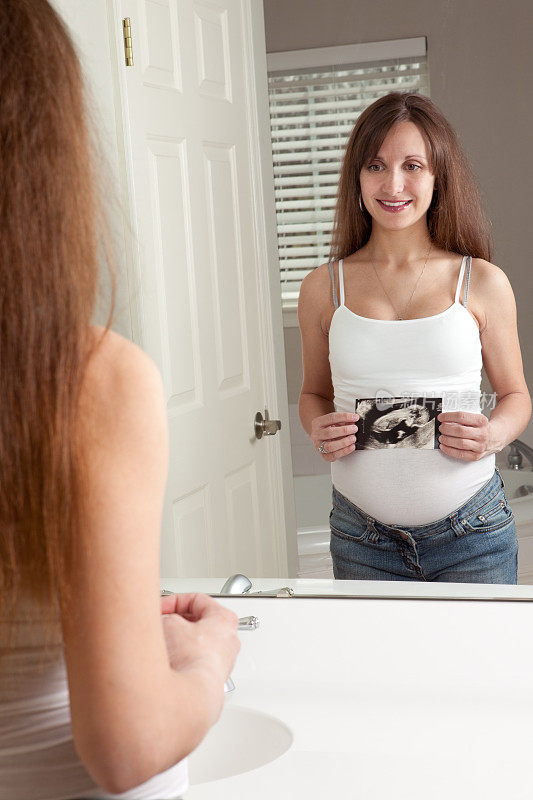 孕妇拿着超声波镜看着镜子