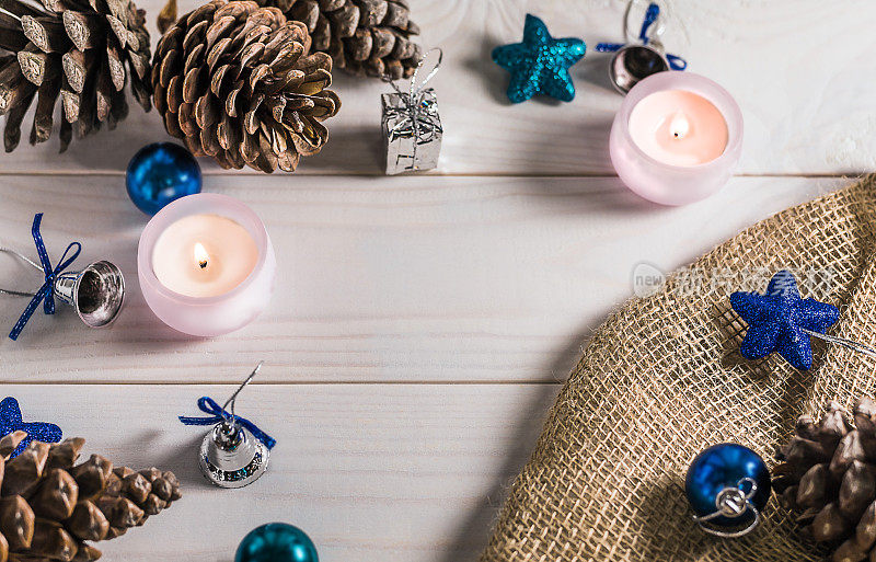 白色木制背景上的圣诞和新年装饰品:球，蜡烛，肿块，星号，麻袋布。