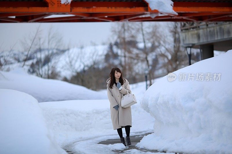 女人走在白雪覆盖的小路上