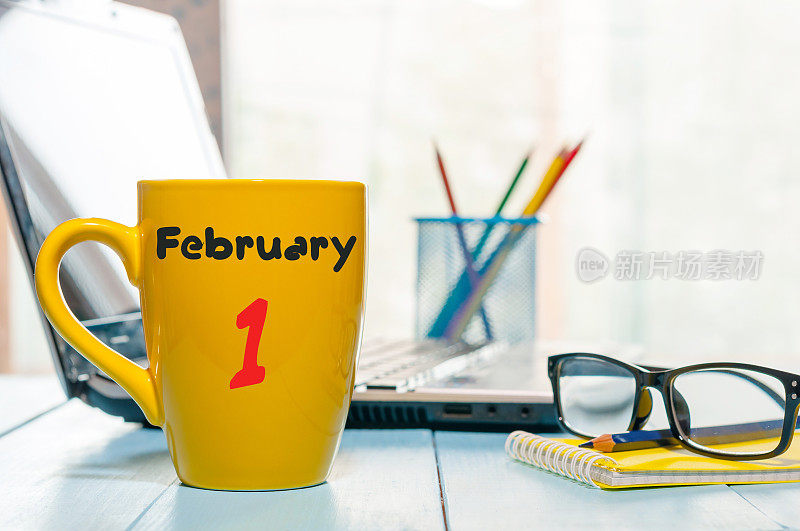 2月1日。月的第一天，日历上的早茶或咖啡杯在工作场所的背景。冬天的时间。文本空白