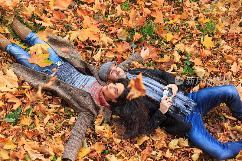 年轻人躺在秋叶铺的地毯上