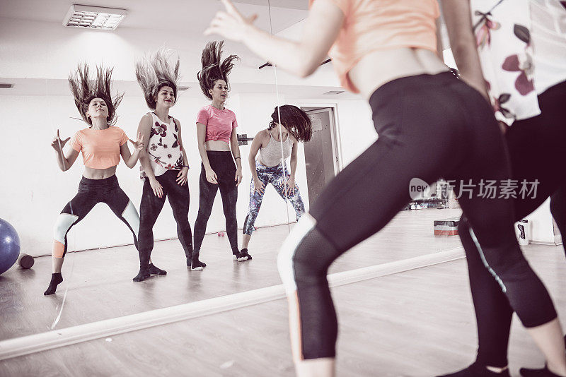 一群可爱的微笑女子在健身房的镜子前练尊巴