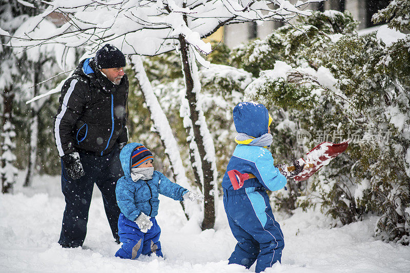 冬天的一天，爷爷和两个孙子在清扫积雪