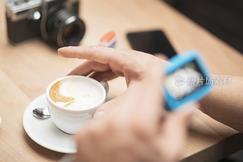 蓄着胡须的英俊男子用动作摄像机拍摄，在咖啡馆餐厅的咖啡休息时间用GoPro相机