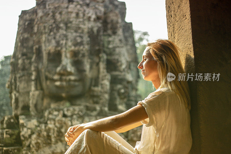 年轻女子凝视着柬埔寨古老的寺庙巴戎寺，吴哥窟建筑群