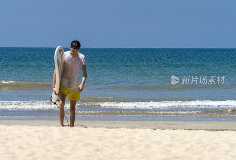 一个年轻人带着冲浪板离开帕卡朗海滩