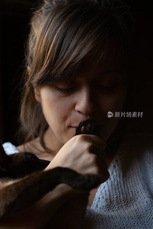 美丽的女人亲吻猫的爪子