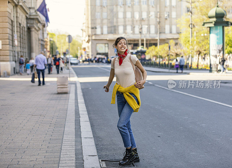 一个快乐女人的肖像。走在城市道路上的年轻女子。快乐的年轻成年妇女微笑着牙齿在户外和走在城市的街道上。