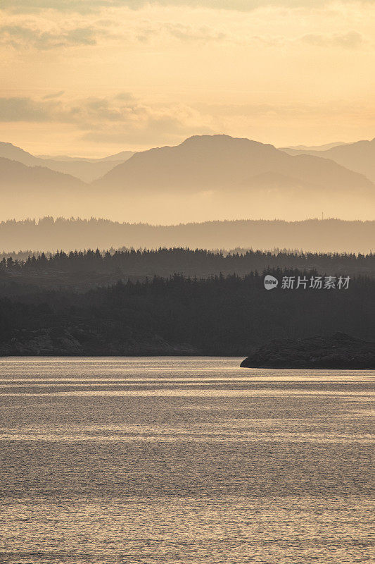 美丽宁静的挪威风景沐浴在一个平静的温暖发光的橙色黎明日出。山景逐渐退到背景中。有足够的空间来放置副本。