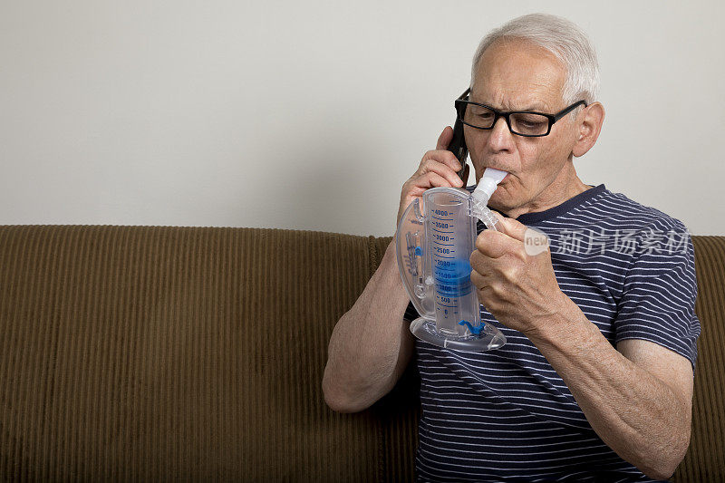 老男人在家拿着肺活量计听着电话