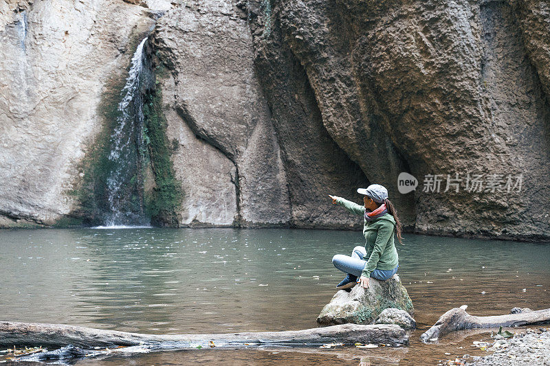 回归自然。独自在瀑布附近旅行。一个快乐的年轻女游客漫步在大自然中。阳光明媚的户外享受。