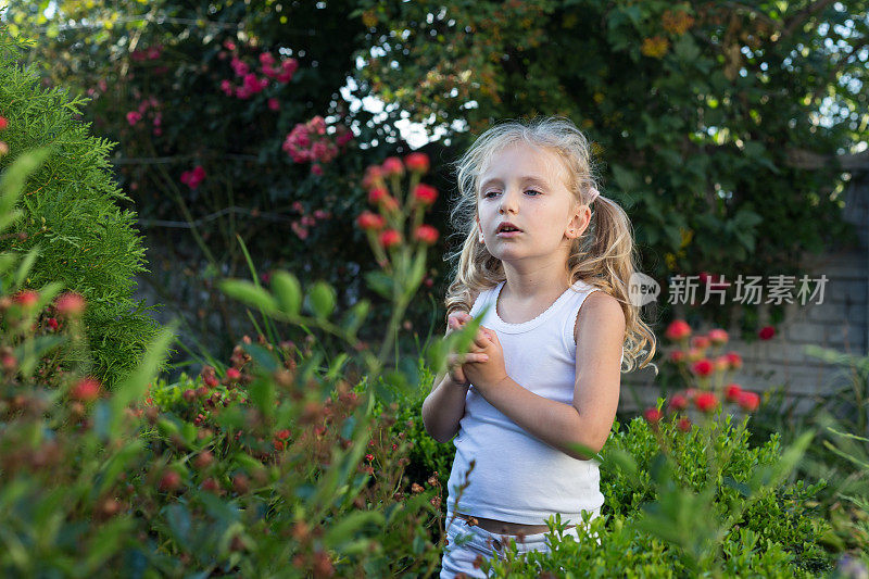 一个小女孩在院子里的花园里散步。
