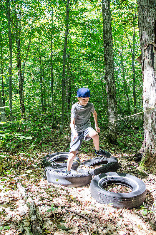 男孩在森林里踩着汽车轮胎奔跑
