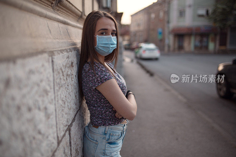 美丽的年轻女子戴着防护面具在街上