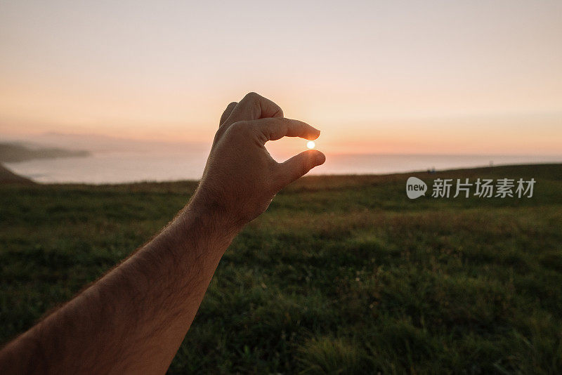 用两根手指在夕阳下捕捉太阳