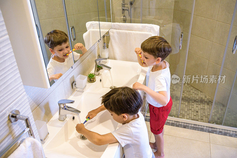 哥哥学着用镜子在浴室里给弟弟刷牙