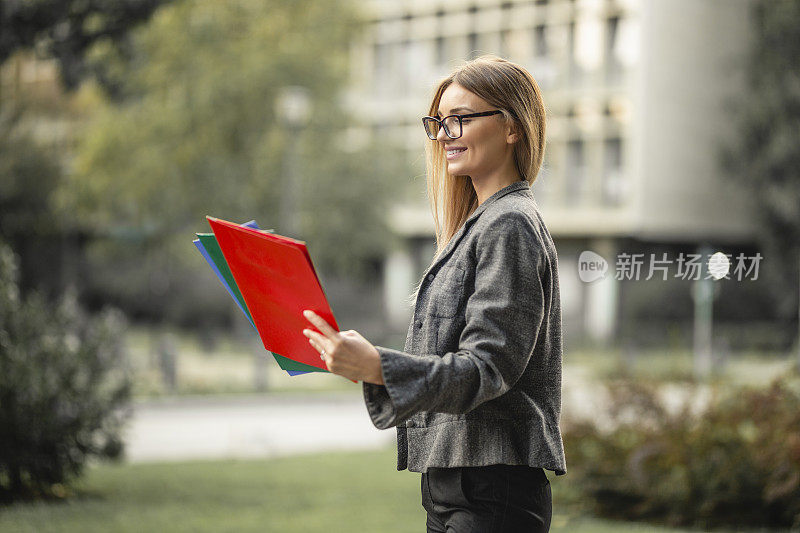 肖像自信的商业女性拿着和阅读文件在户外