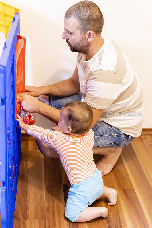 爸爸和宝宝组装塑料玩具屋。父亲和儿子之间的乐趣。