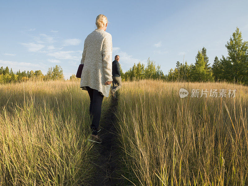 女人沿着一条狭窄的小路穿过高高的草丛走向男人