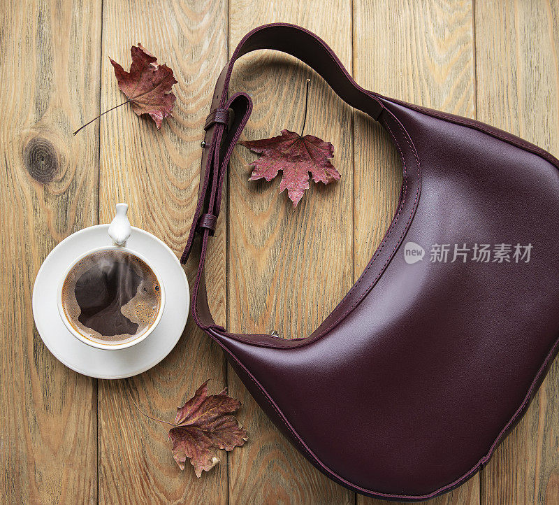 皮包，咖啡杯和秋天的树叶在一个木制的背景
