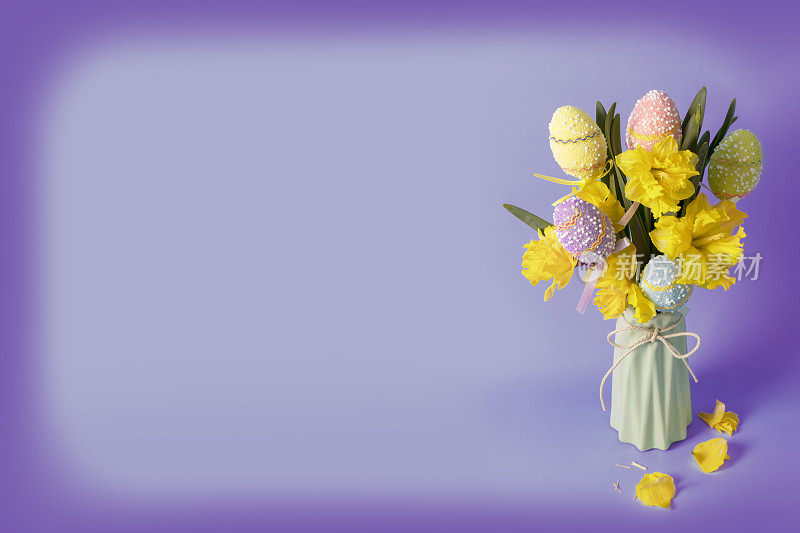 紫色背景上的花瓶里装着水仙花和复活节彩蛋