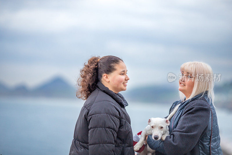 妈妈和十几岁的女儿和他们的杰克罗素梗在旅行中享受风景