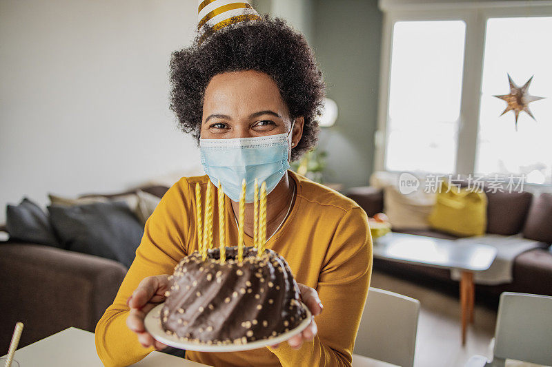 一名戴口罩的非洲妇女在疫情期间在家庆祝生日的肖像