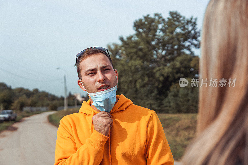 一名男子扯下面罩在街上说话