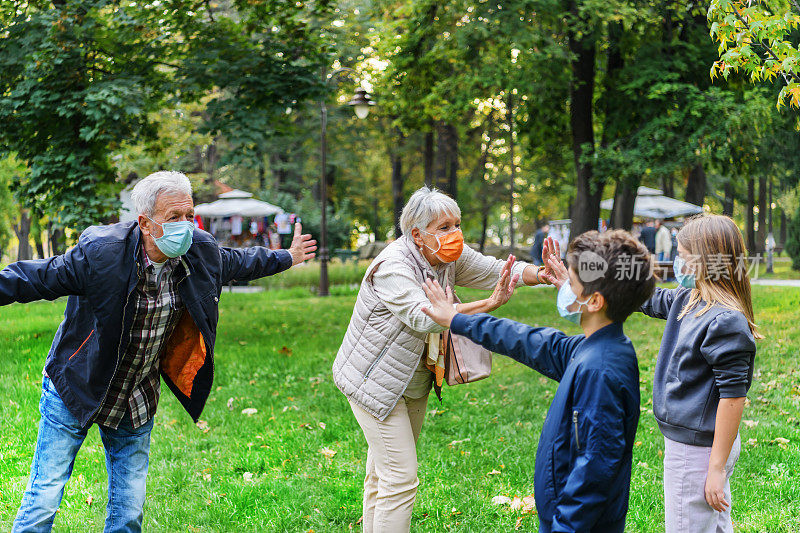 祖父母和他们的孙子用肘部打招呼，以避免传播病毒。