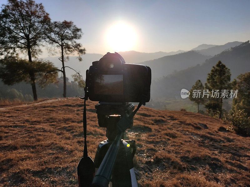 相机在三脚架和摄影视图相机与模糊焦点的日落景观