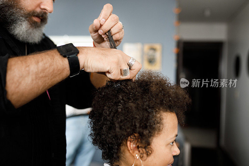 一位男性发型师给一位黑人年轻女子做发型