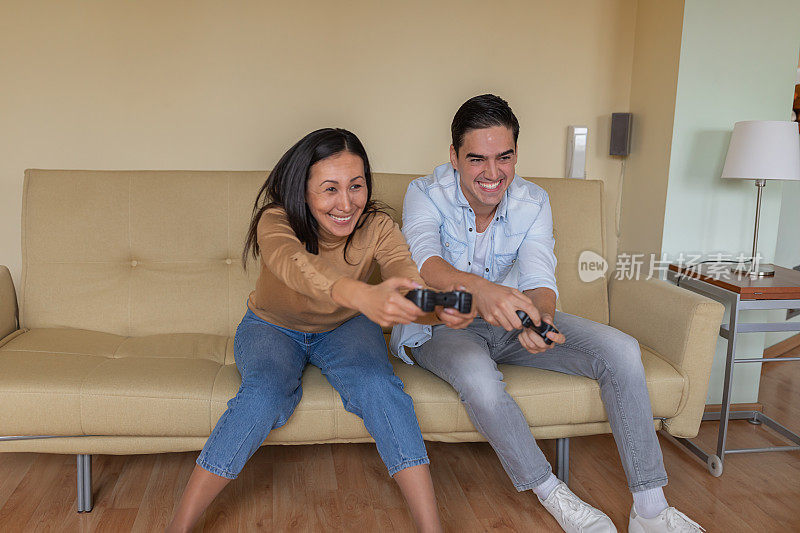 一个年轻女子在家玩电脑游戏的时候和她的男朋友玩得很开心。
