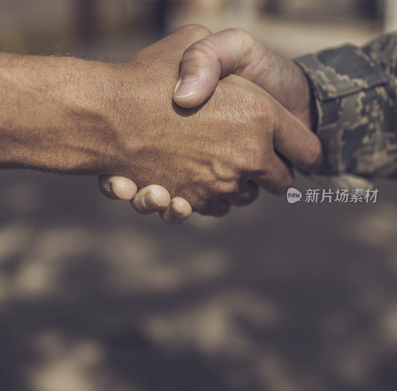 身穿军装的士兵与身份不明的男性握手