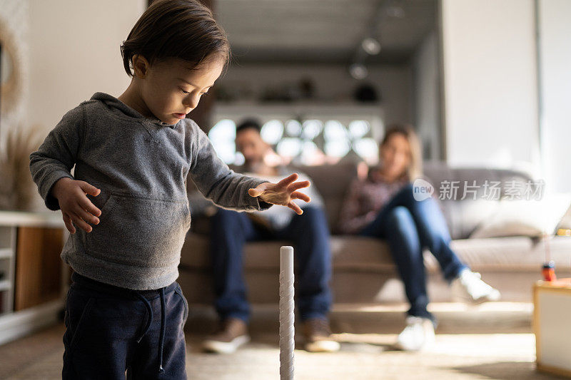 特别的男孩在家里玩耍，父母在后台