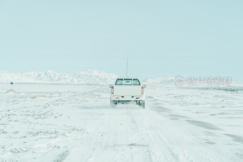 越野皮卡车以雪山为背景，站在雪地上