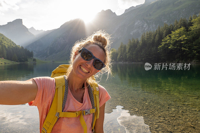 在瑞士，一名年轻女子徒步与美丽的高山湖泊合影。她喜欢大自然和清新的环境