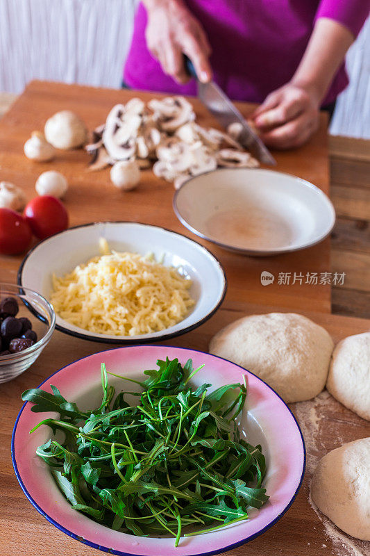 家里做披萨，把蘑菇切成薄片，餐桌上的食材